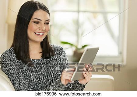 Hispanic woman using digital tablet on sofa View Large Photo Image Stock Photograph - Hispanic woman using digital tablet on sofa. Fotosearch