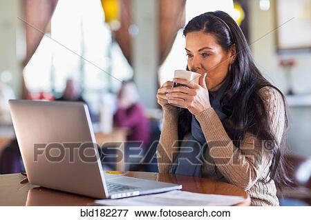 Hispanic woman using laptop in cafe View Large Photo Image Stock Photo - Hispanic woman using laptop in cafe. Fotosearch