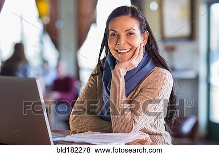 Stock Photo - Hispanic woman using laptop in cafe. Fotosearch