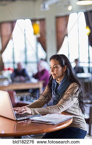 Hispanic woman using laptop in cafe View Large Photo Image Stock Photograph - Hispanic woman using laptop in cafe. Fotosearch