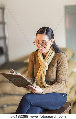 Stock Photo - Hispanic woman writing on clipboard. Fotosearch