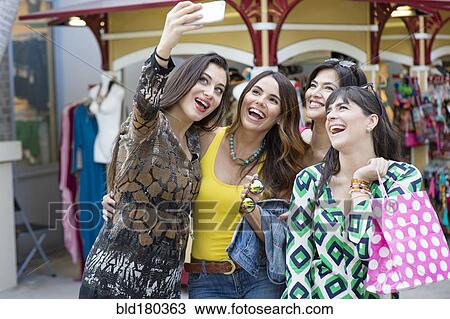 Stock Image - Hispanic women taking selfie outdoors. Fotosearch