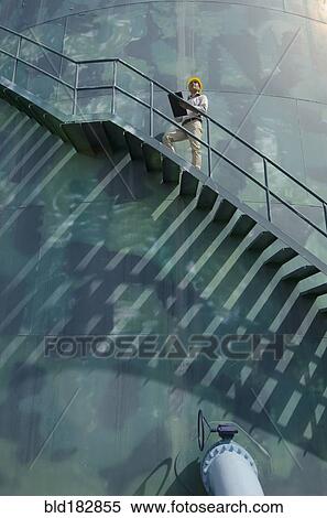 Stock Photography - Hispanic worker standing on silo staircase. Fotosearch