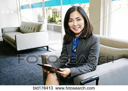 Stock Image - Japanese businesswoman using digital tablet in office. Fotosearch