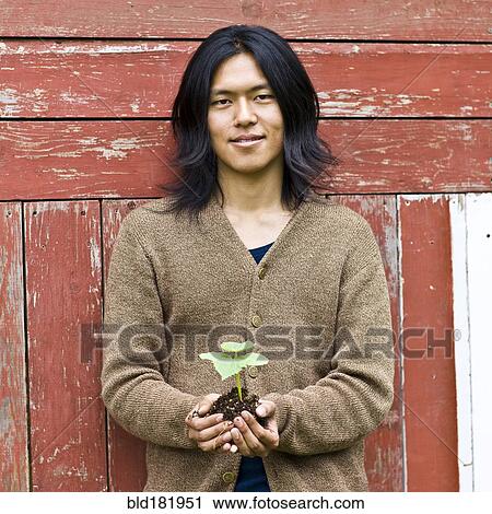 Japanese man holding potted plant outdoors View Large Photo Image Stock Image - Japanese man holding potted plant outdoors. Fotosearch
