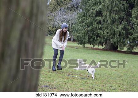 Picture - Japanese woman playing with dog in park. Fotosearch