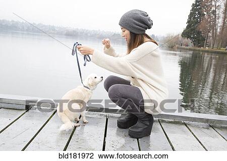 Stock Image - Japanese woman walking dog near lake. Fotosearch
