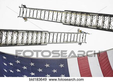 Stock Photo - Low angle view of crane ladders and American flag. Fotosearch