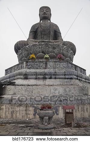 Stock Image - Low angle view of stone Buddha statue. Fotosearch