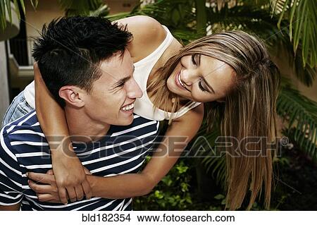Picture - Man carrying girlfriend piggyback outdoors. Fotosearch