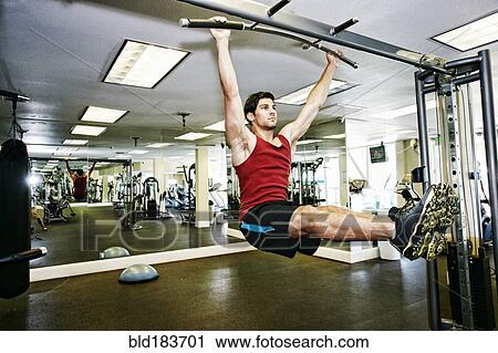 Man doing pull-ups in gymnasium View Large Photo Image Stock Image - Man doing pull-ups in gymnasium. Fotosearch