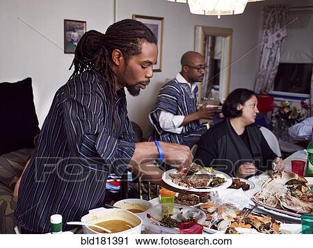 Stock Image - Man serving food at holiday dinner. Fotosearch
