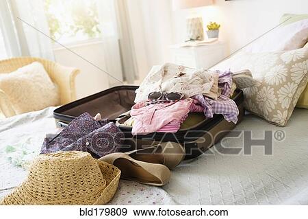 Stock Photo - Messy suitcase on bed. Fotosearch