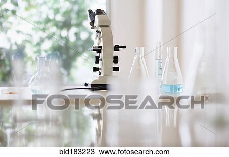 Stock Image - Microscope and beakers in laboratory. Fotosearch