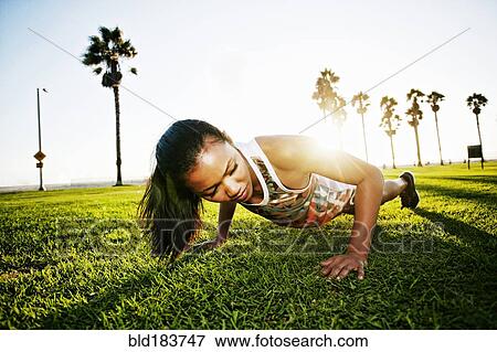 Stock Photo - Mixed race athlete doing push-ups in park. Fotosearch