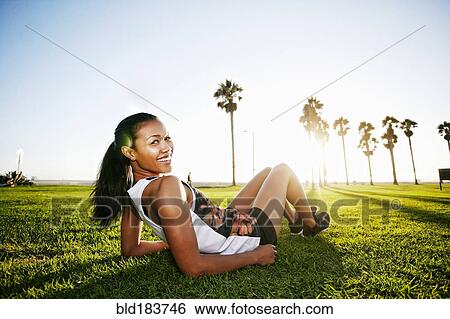 Stock Photograph - Mixed race athlete laying in park. Fotosearch