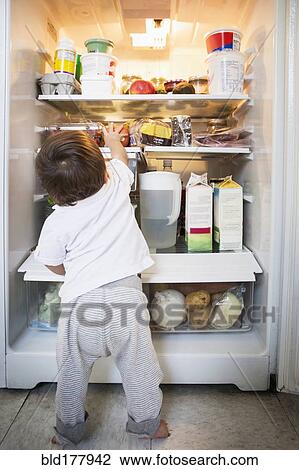 Stock Image - Mixed race baby boy exploring refrigerator. Fotosearch