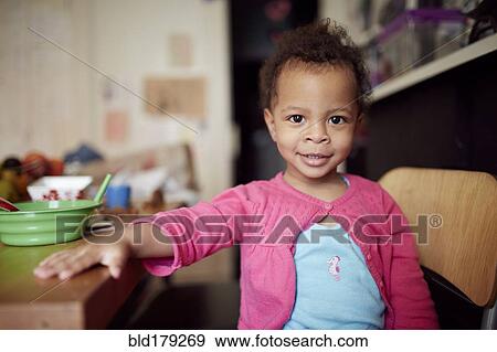 Mixed race baby girl sitting at table View Large Photo Image Stock Photo - Mixed race baby girl sitting at table. Fotosearch