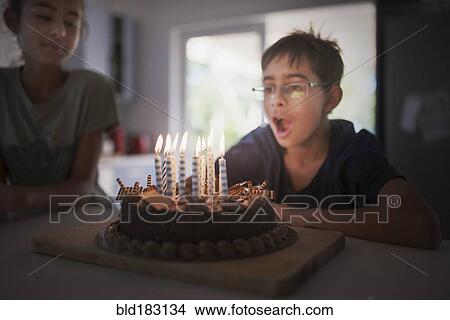 Picture - Mixed race boy blowing birthday candles. Fotosearch