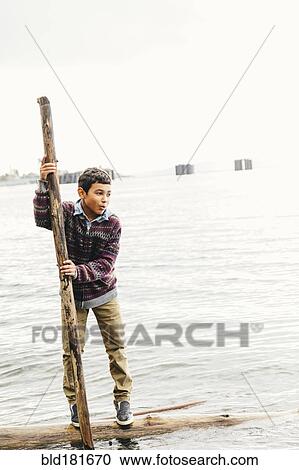 Mixed race boy playing on log in lake View Large Photo Image Stock Image - Mixed race boy playing on log in lake. Fotosearch