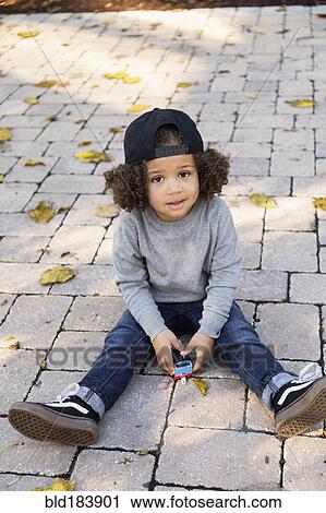 Mixed race boy sitting on brick patio View Large Photo Image Stock Image - Mixed race boy sitting on brick patio. Fotosearch