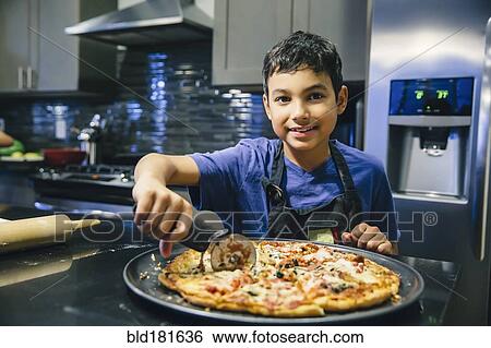 Mixed race boy slicing pizza in kitchen View Large Photo Image Stock Photograph - Mixed race boy slicing pizza in kitchen. Fotosearch