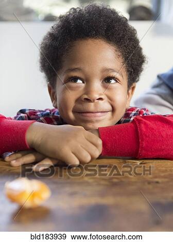 Stock Photo - Mixed race boy smiling at table. Fotosearch