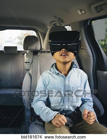 Picture - Mixed race boy using virtual reality goggles in car. Fotosearch