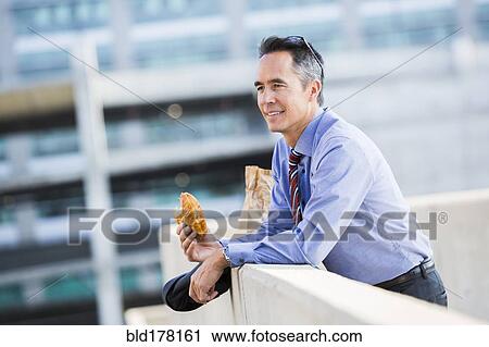 Mixed race businessman eating on urban rooftop View Large Photo Image Stock Image - Mixed race businessman eating on urban rooftop. Fotosearch