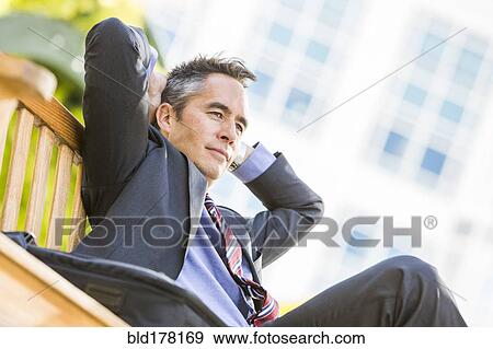 Mixed race businessman sitting outdoors View Large Photo Image Stock Photo - Mixed race businessman sitting outdoors. Fotosearch
