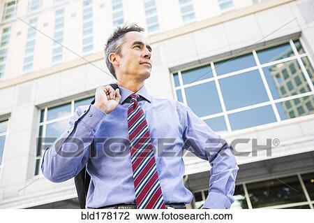 Stock Image - Mixed race businessman standing outdoors. Fotosearch
