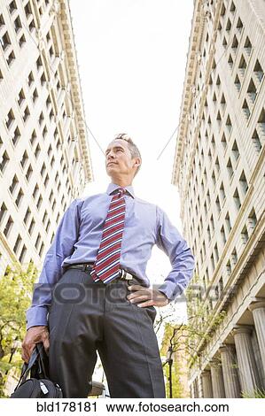 Stock Image - Mixed race businessman standing outdoors. Fotosearch