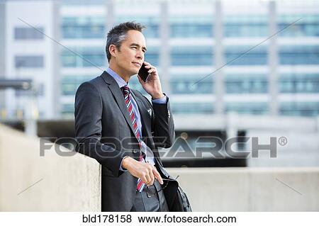 Stock Photo - Mixed race businessman talking on cell phone. Fotosearch