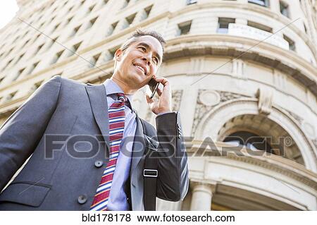 Stock Photo - Mixed race businessman talking on cell phone outdoors. Fotosearch