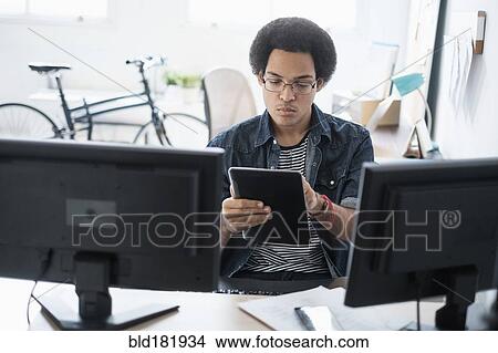 Mixed race businessman using digital tablet in office View Large Photo Image Picture - Mixed race businessman using digital tablet in office. Fotosearch