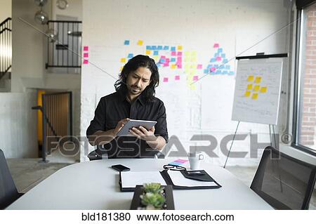 Stock Image - Mixed race businessman using digital tablet in office. Fotosearch