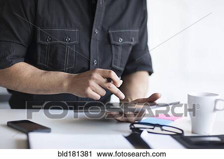 Stock Image - Mixed race businessman using digital tablet in office. Fotosearch