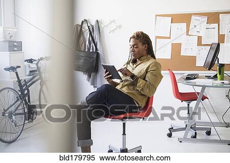 Stock Photography - Mixed race businessman using digital tablet in office. Fotosearch