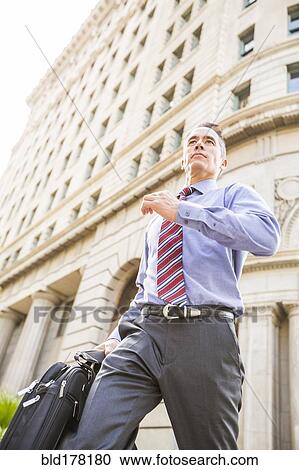 Stock Image - Mixed race businessman walking outdoors. Fotosearch