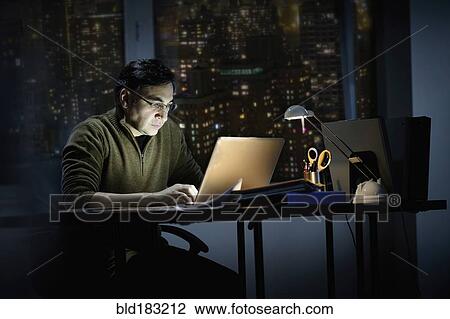 Stock Image - Mixed race businessman working late in office. Fotosearch
