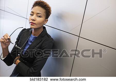 Stock Image - Mixed race businesswoman holding eyeglasses. Fotosearch