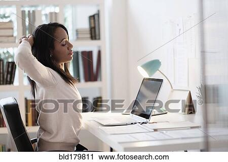 Mixed race businesswoman stretching at desk View Large Photo Image Stock Image - Mixed race businesswoman stretching at desk. Fotosearch