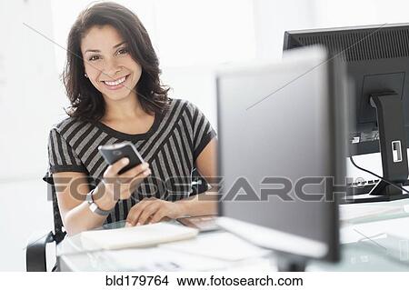 Picture - Mixed race businesswoman using cell phone. Fotosearch