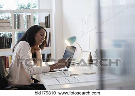 Stock Image - Mixed race businesswoman using cell phone. Fotosearch