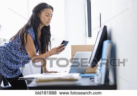 Stock Photo - Mixed race businesswoman using cell phone. Fotosearch