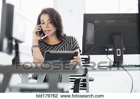 Stock Image - Mixed race businesswoman using digital tablet. Fotosearch