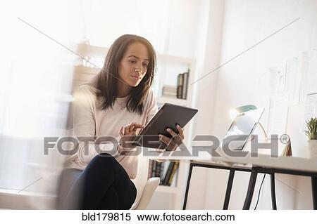Stock Photography - Mixed race businesswoman using digital tablet. Fotosearch