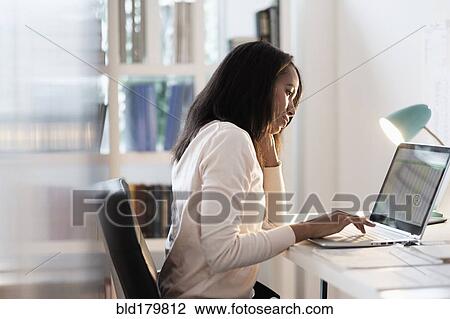 Stock Image - Mixed race businesswoman using laptop. Fotosearch