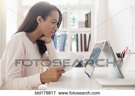 Stock Photo - Mixed race businesswoman using laptop. Fotosearch
