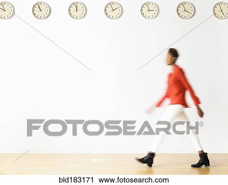 Mixed race businesswoman walking under clocks View Large Photo Image Stock Image - Mixed race businesswoman walking under clocks. Fotosearch